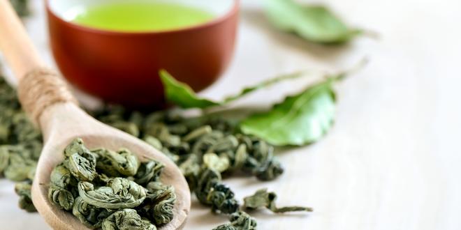 Dried green tea leaves and a fresh hot cup