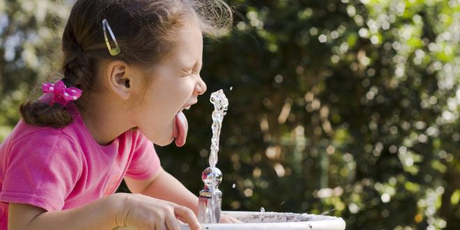 A little girl drinking from a bubbler fountain