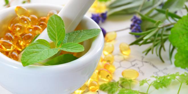 Soft gel supplements in a mortar surrounded by herbs