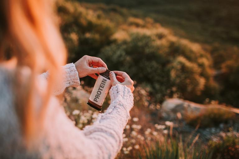 A hiker opening a protein bar